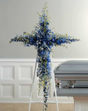 Blue and white floral cross-shaped funeral spray on an easel