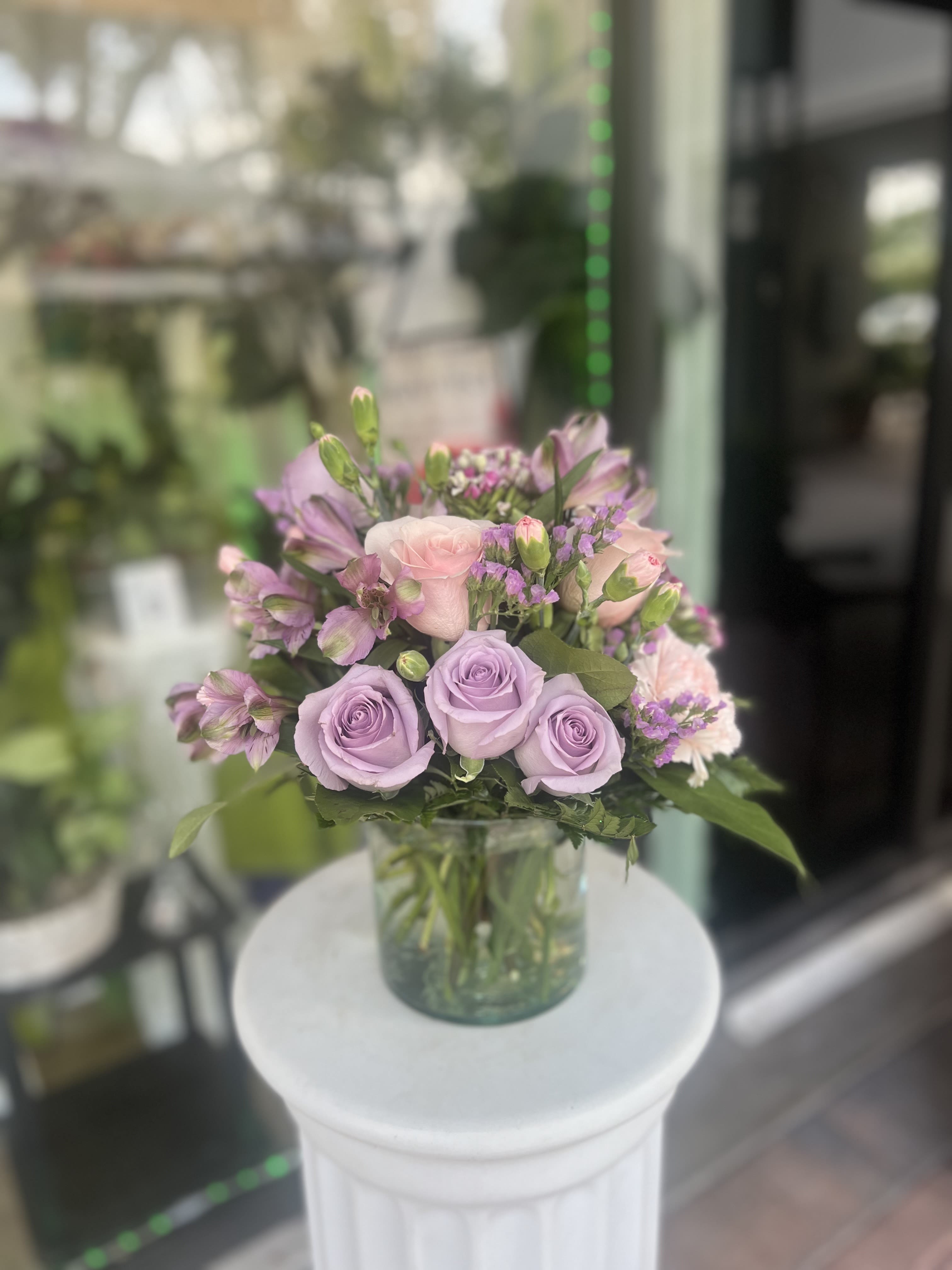 Lavender and pink roses arranged in a clear glass vase