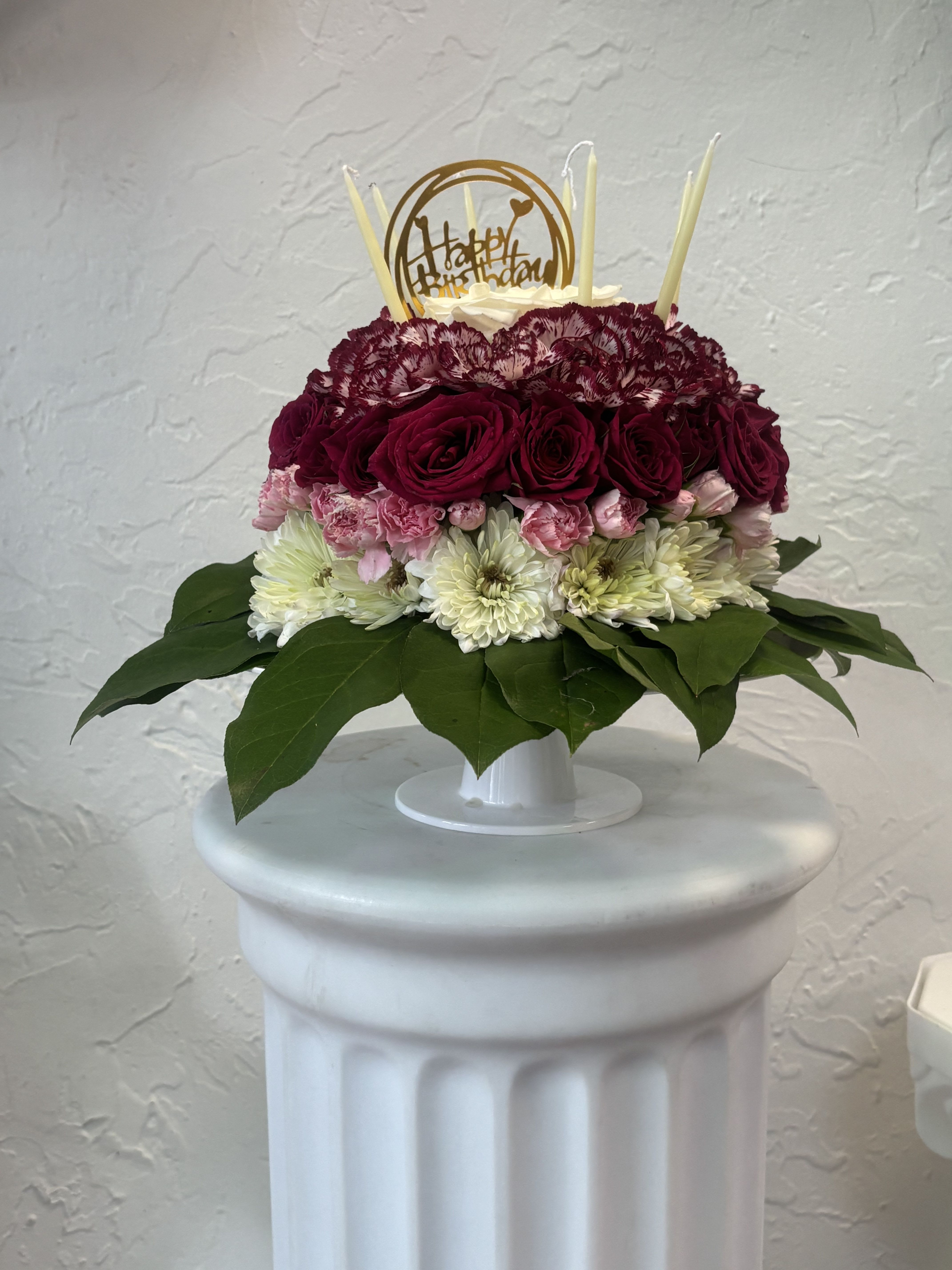 Blooming Birthday Cake - Celebrate a birthday with a delightful "Blooming Birthday Cake" floral arrangement adorned with light purple flowers, white daisies, and three candles for a touch of festivity. With our same-day flower delivery, you can promptly send this charming and creative bouquet that mimics the joy of a birthday cake. The light purple blooms and white daisies add a soft and elegant touch, while the candles bring a celebratory flair. Order now to surprise and delight someone special on their birthday with this unique and blooming birthday cake, a perfect and cheerful alternative to a traditional cake. 