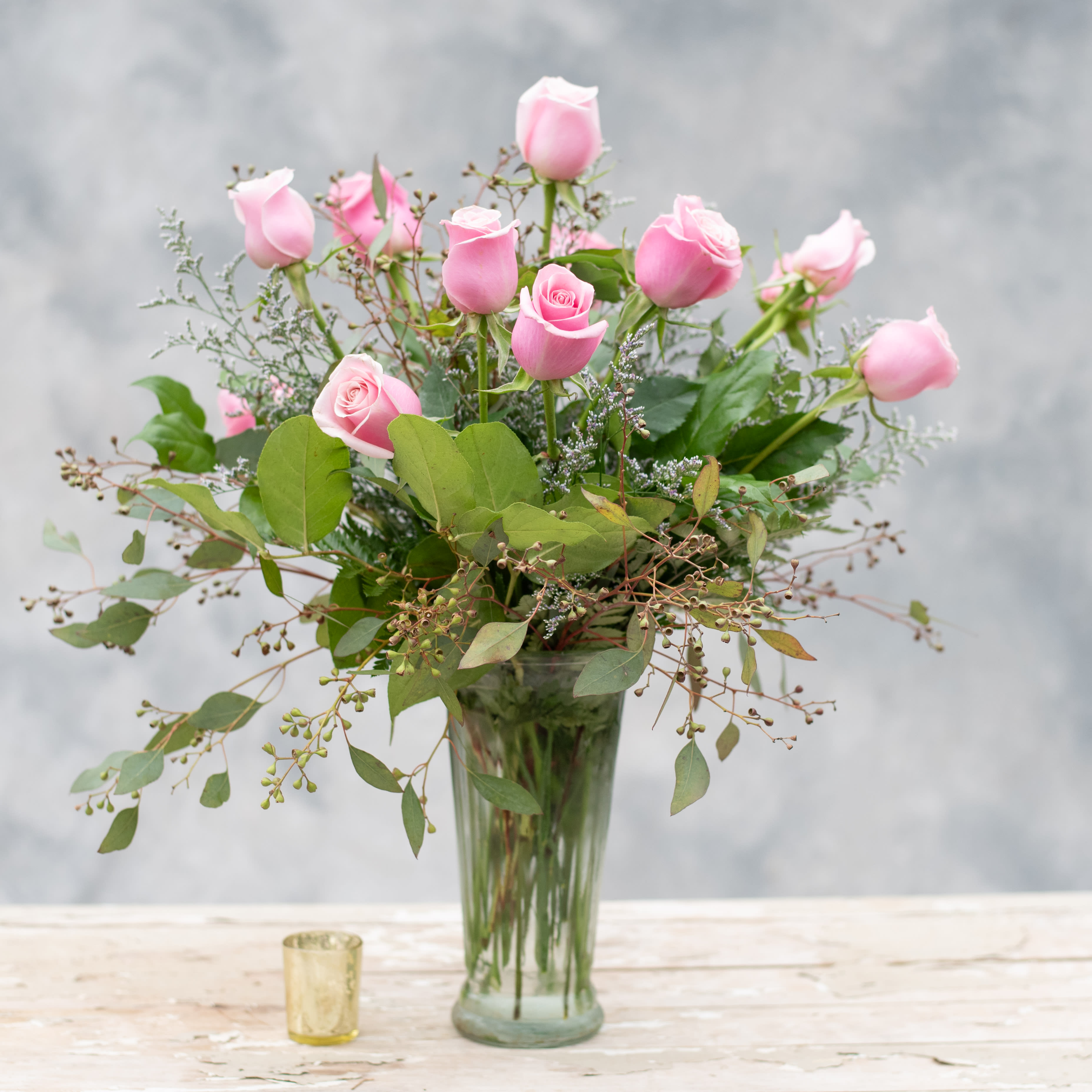 Pink roses arranged in a clear glass vase with greenery