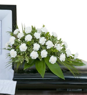 White floral casket spray with green foliage
