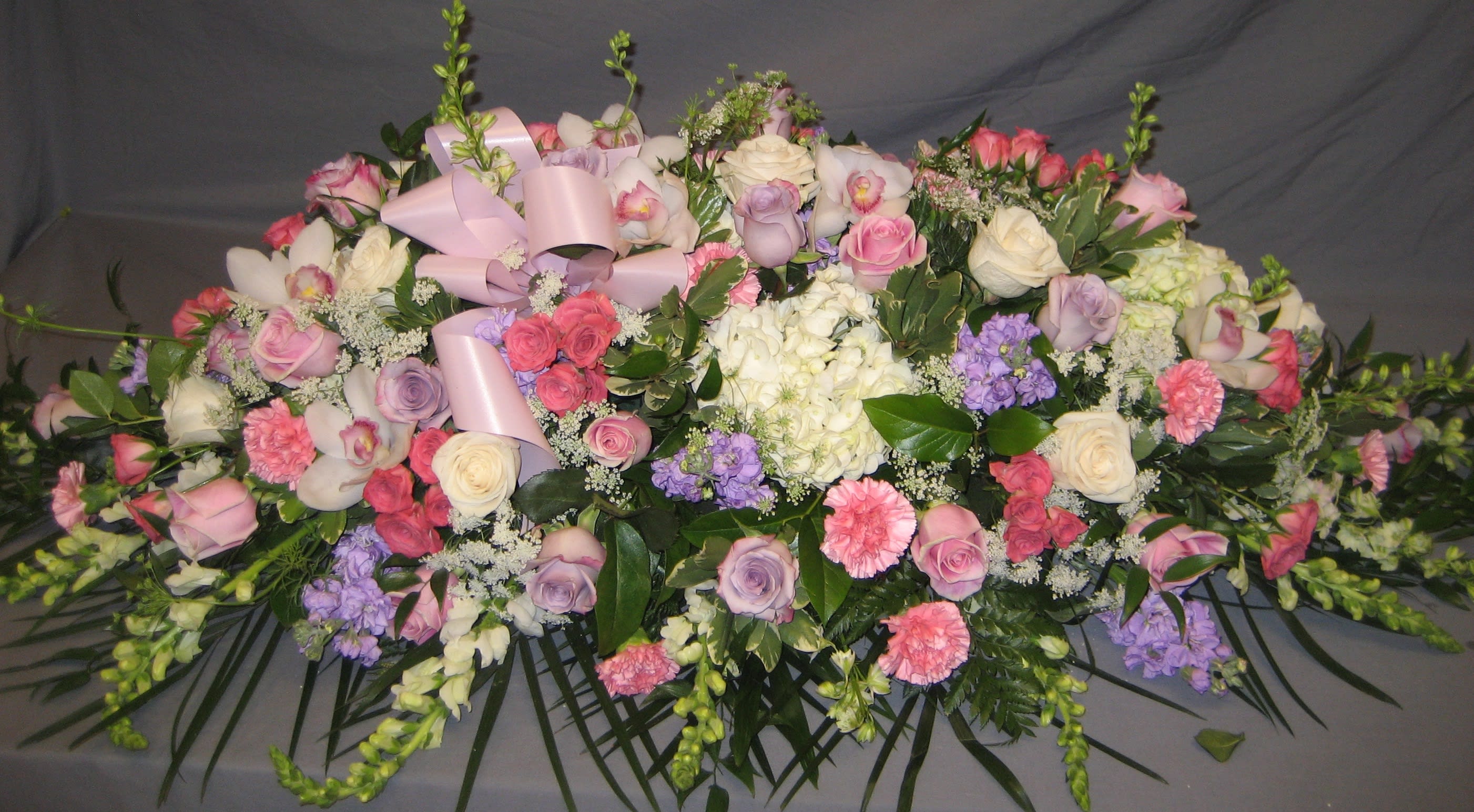 Pink &amp; Purple Casket Spray C3 - A casket spray is the largest piece at a service and this pastel design is a lovely tribute. Upgrading to Deluxe or Premium will add more flowers to your design. **Ribbon Script is an additional $10  