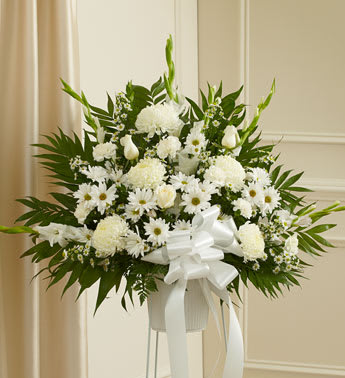 White floral standing arrangement with a ribbon on a pedestal