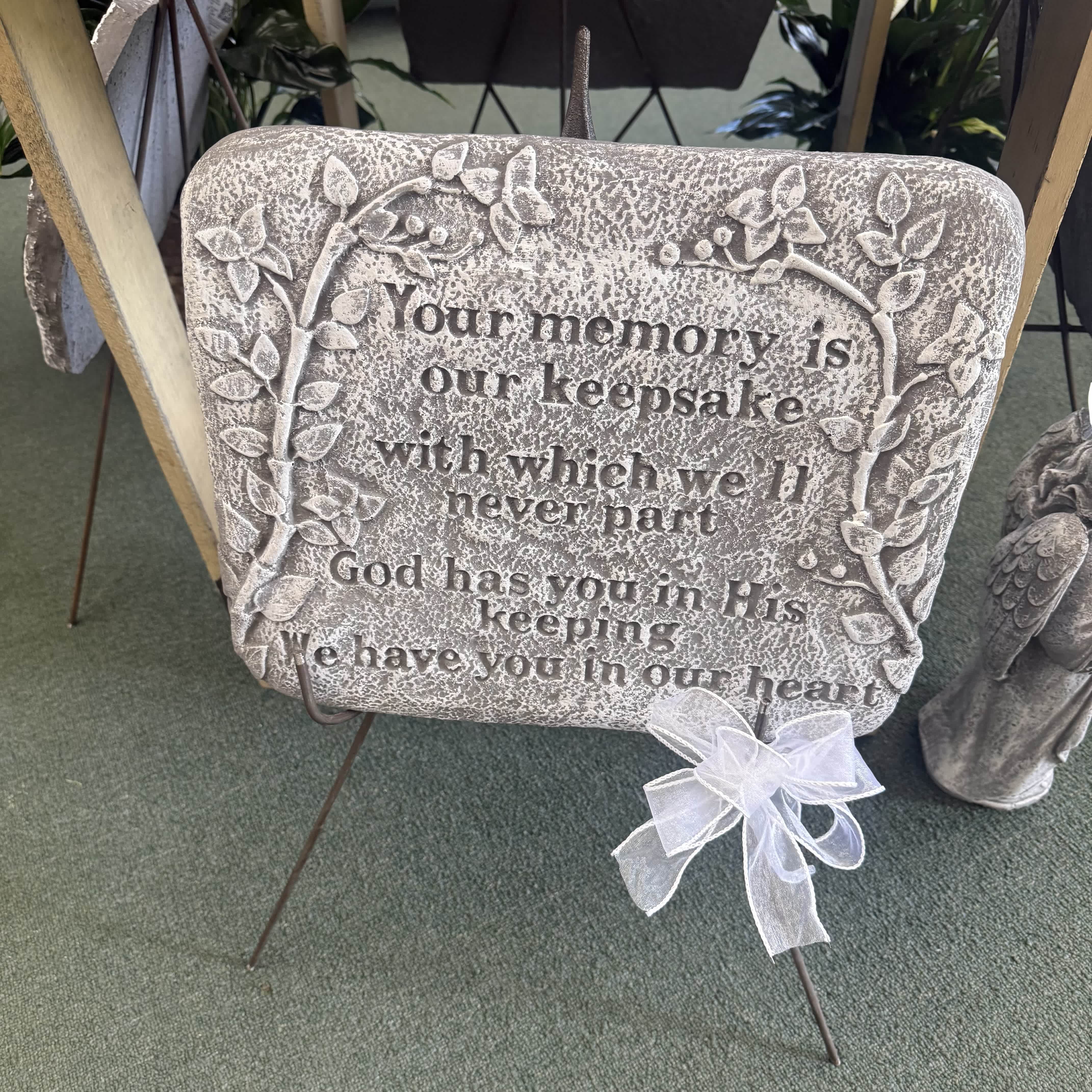 Memorial stone plaque with a white ribbon bow on a metal stand