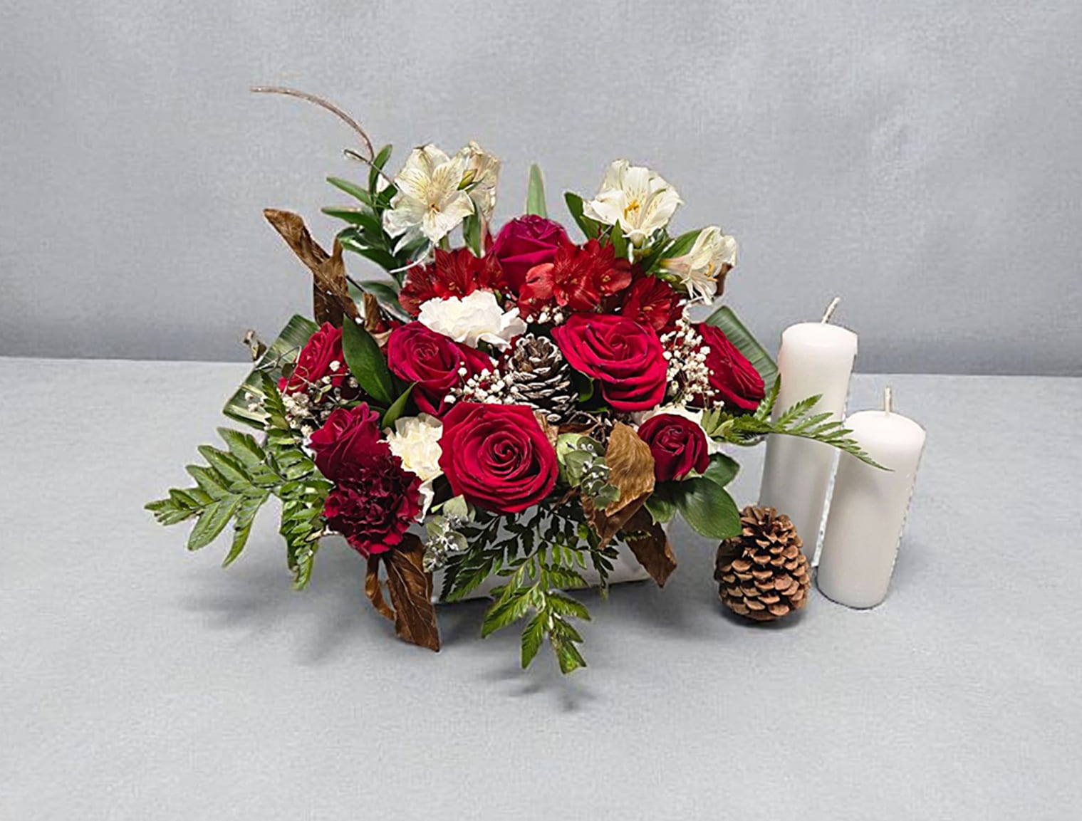Christmas Carol - This arrangement sings with joy with is beautiful display of red roses, and evergreens. Great for a table centerpiece or mantel.  