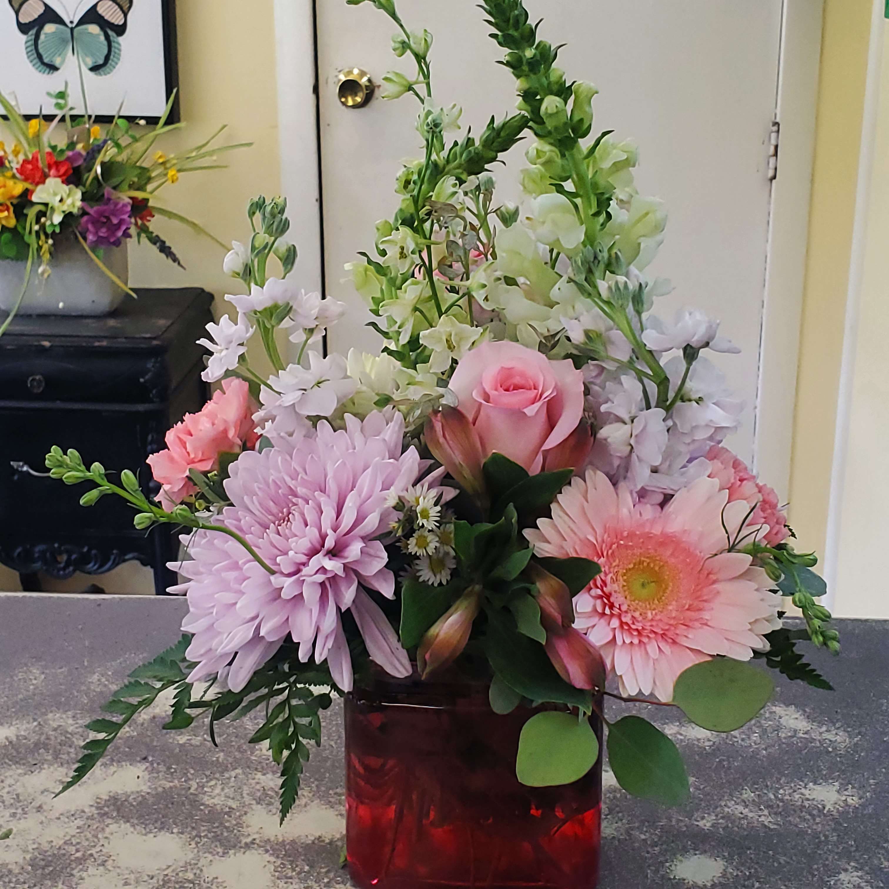 Pink and white mixed flower arrangement in a red glass vase