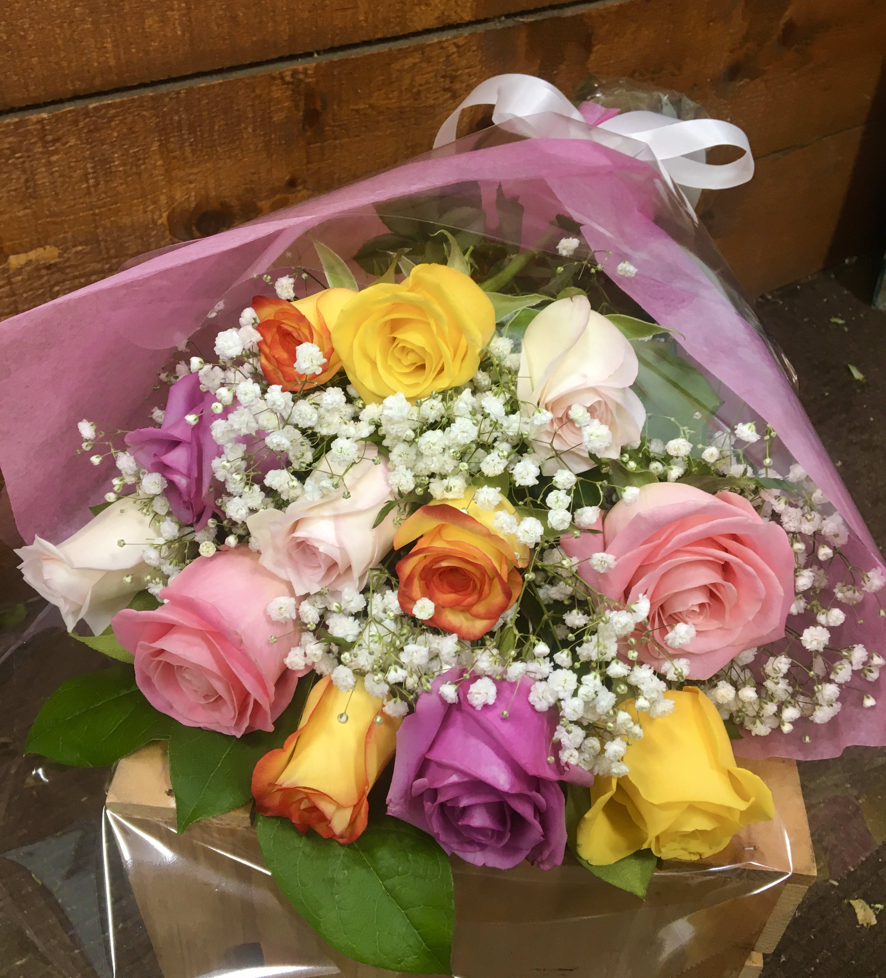Bouquet of multicolored roses with baby's breath in pink wrap