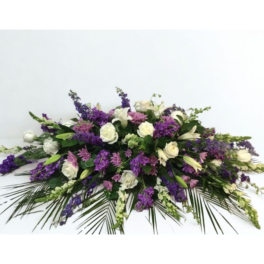 Low floral arrangement with white roses, lilies, and purple blooms