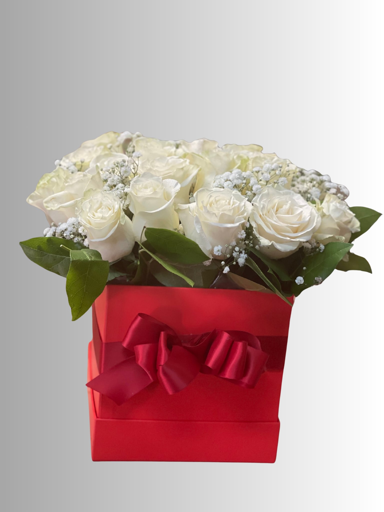 White roses in a red gift box with a ribbon bow