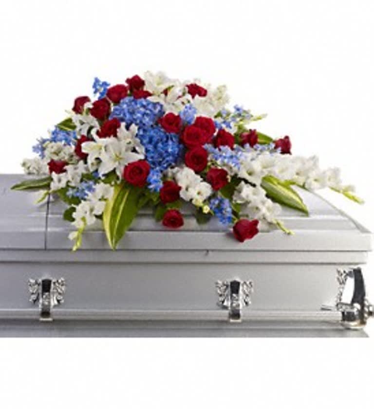 Red, white, and blue floral arrangement on a silver casket