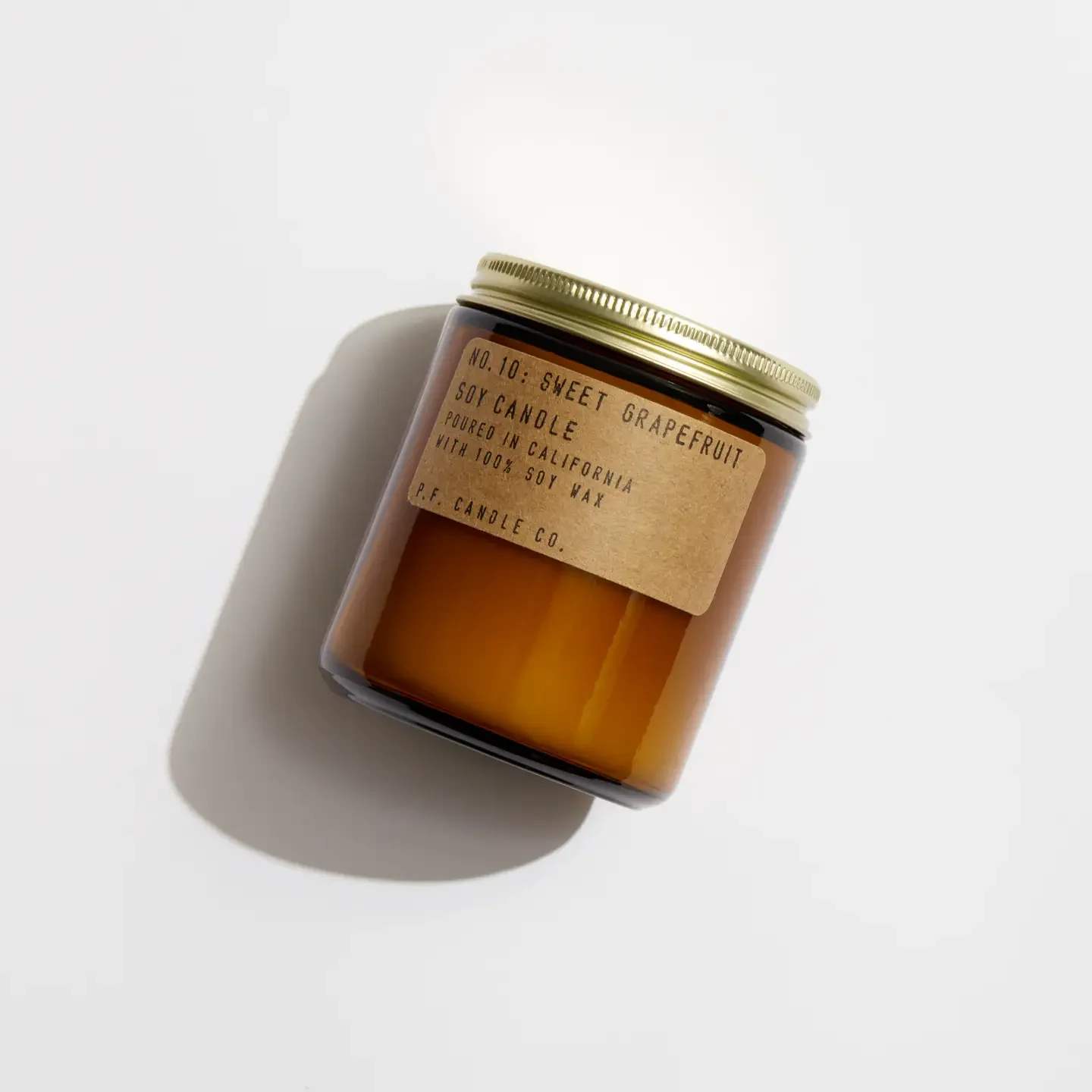 Amber jar candle with a gold lid and paper label