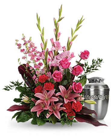 Pink lilies and roses arranged beside a silver urn.