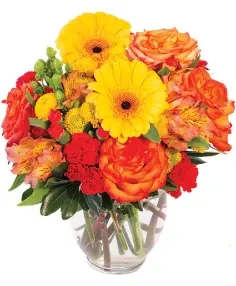 Bouquet of yellow gerbera daisies and orange roses in a clear glass vase