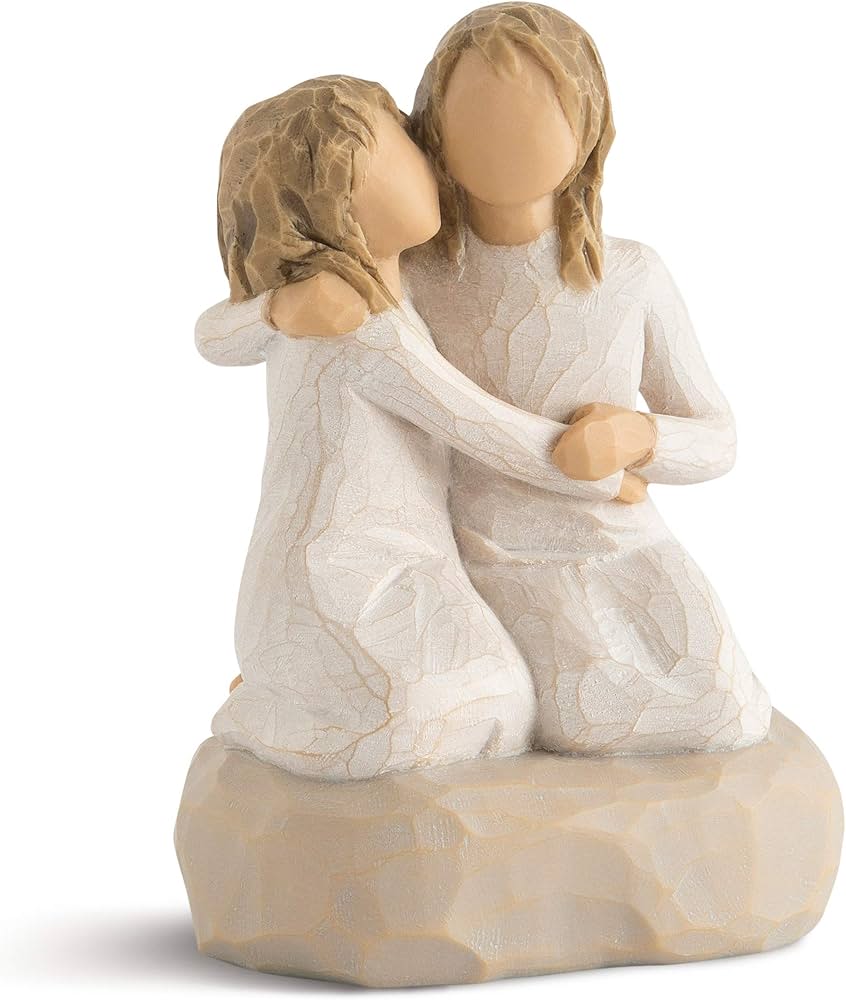 Two faceless figurines embracing in white dresses on a beige base