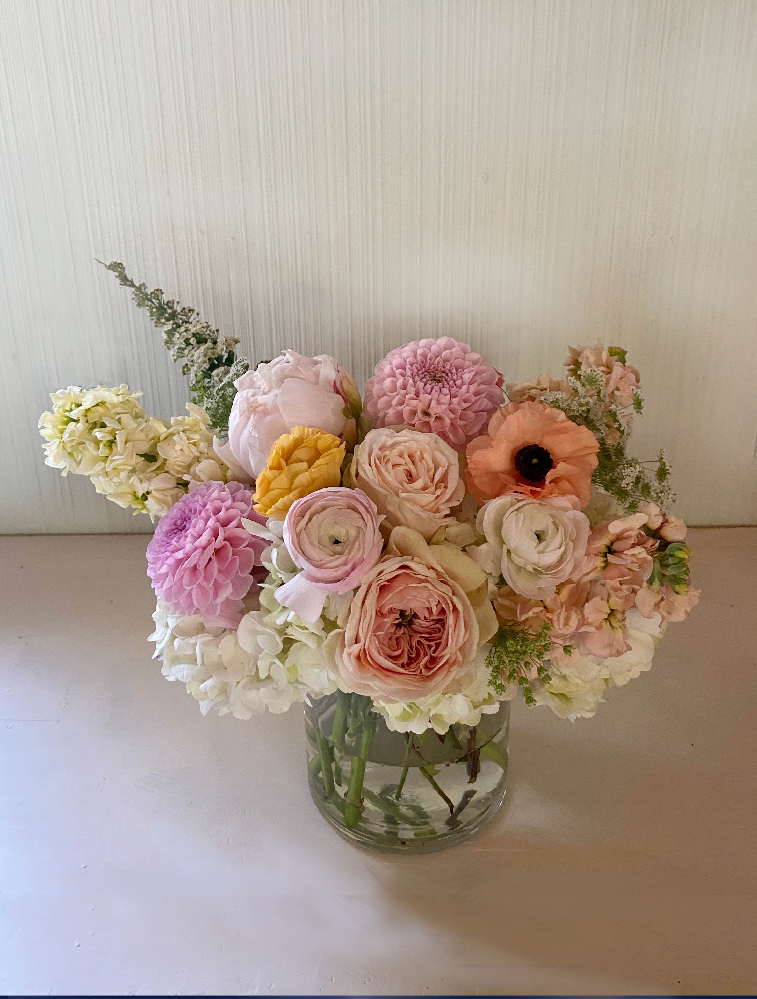 Arabella arrangement - Elegant and whimsical arrangement of gorgeous pastels mixed with hints of light yellow and golden coral colors. Garden roses, peonies or dahlias (when in season), ranunculus and other sourced seasonal flowers of the highest quality make this arrangement a stunning gift or the perfect bright addtion to the dinner table. The flowers are arranged in a clear 5' by 7' vase. Blomst LA only uses fresh, high quality flowers, all carefully selected every day to fit your flower order.  We offer a personal hand delivery by our own delivery staff and guarantee the flowers will look perfect, when they arrive. We deliver in Glendale, Pasadena, Eagle Rock, Hollywood, Burbank, Beverly Hills - and everywhere else in Greater Los Angeles.