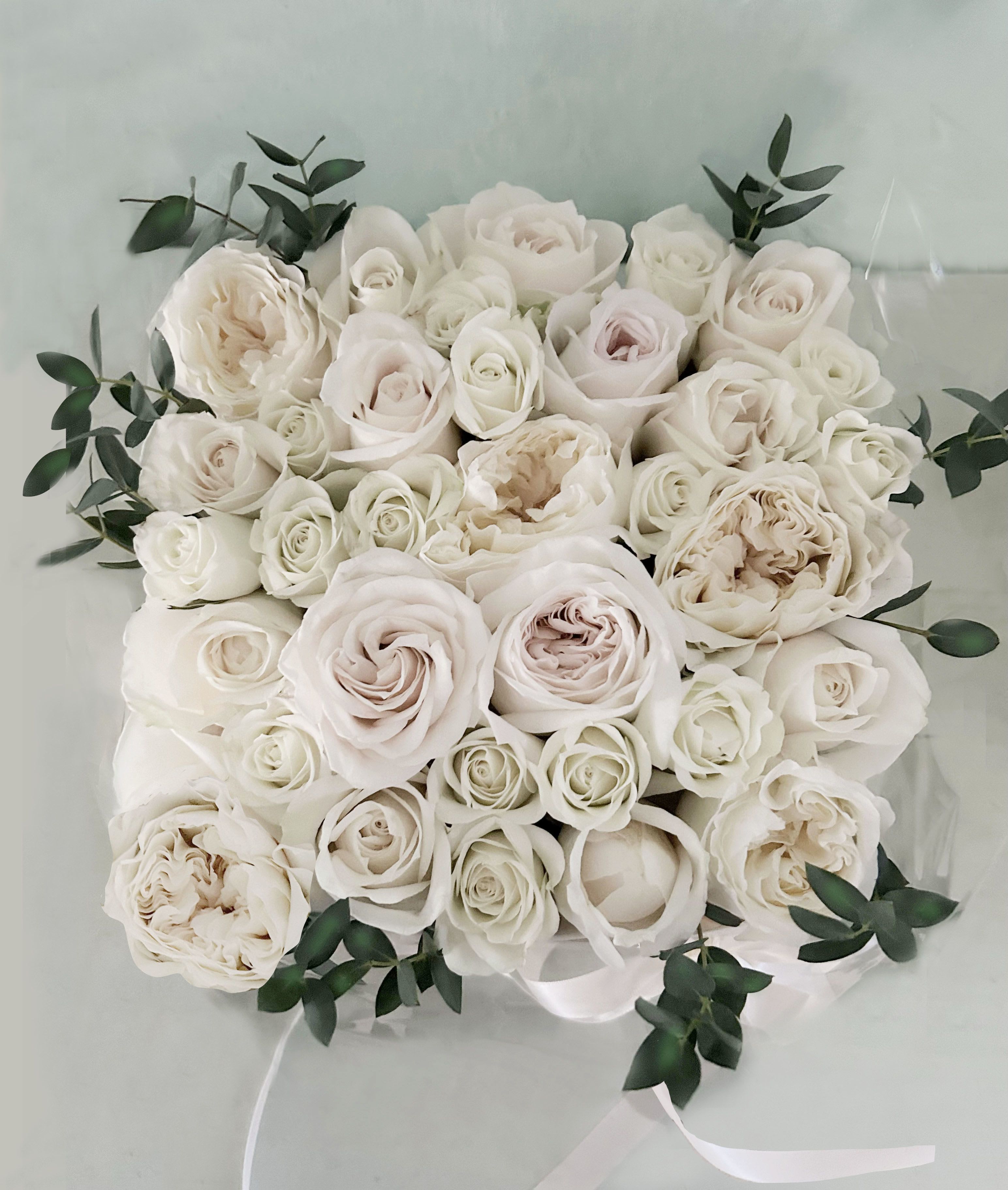 The Blomst Rose box - white - Beautiful signature Blomst Rose box. The light and natural wooden boxis packed full of white roses: garden roses, spray roses and roses; all of the highest quality. The wooden box is 8" b 8" and 4" tall. Wrapped in silk paper and cellophane for an exclusive look. You can upgrade to Deluxe and premium for more roses volume. 