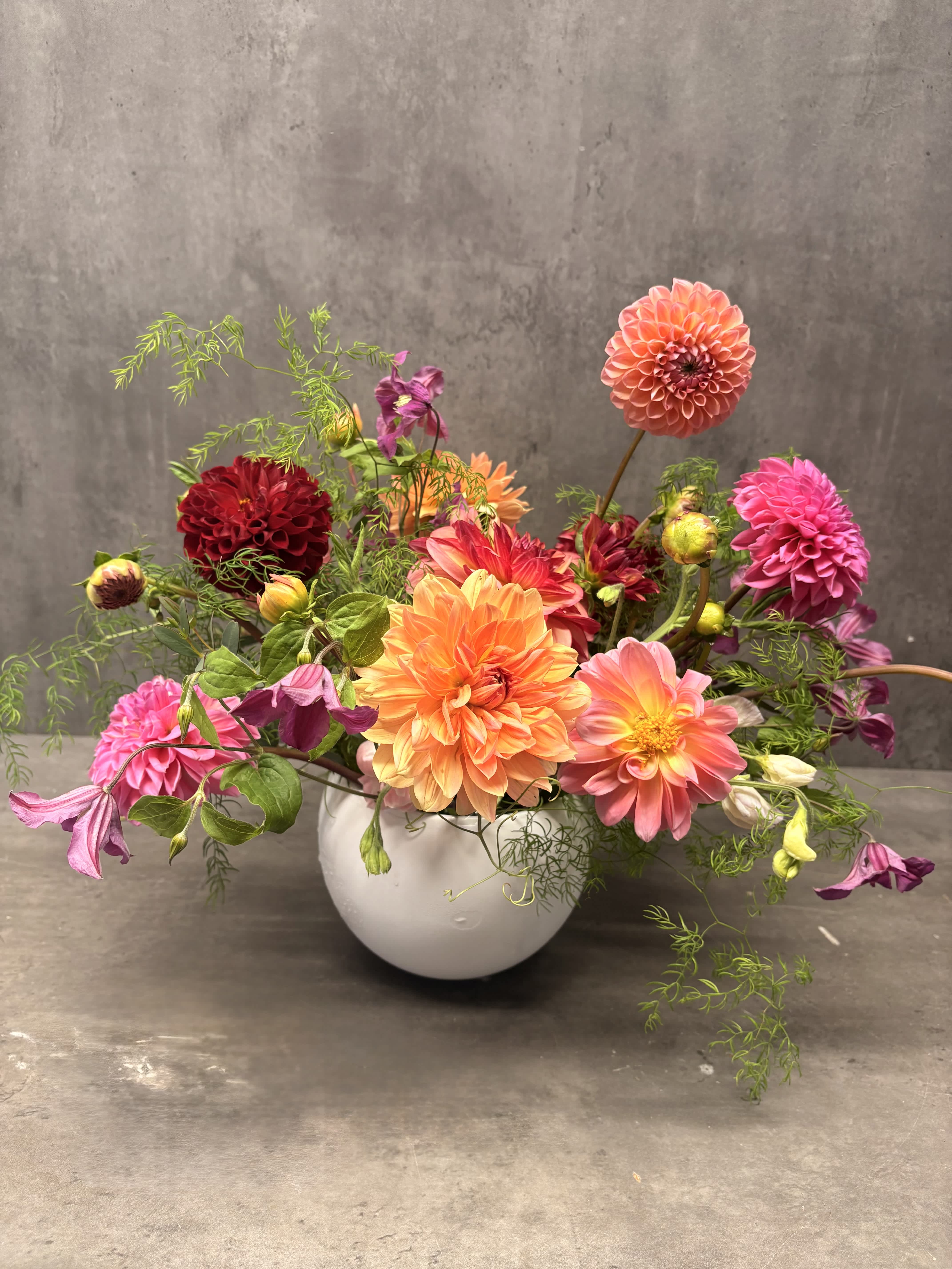 Colorful dahlia arrangement in a white vase