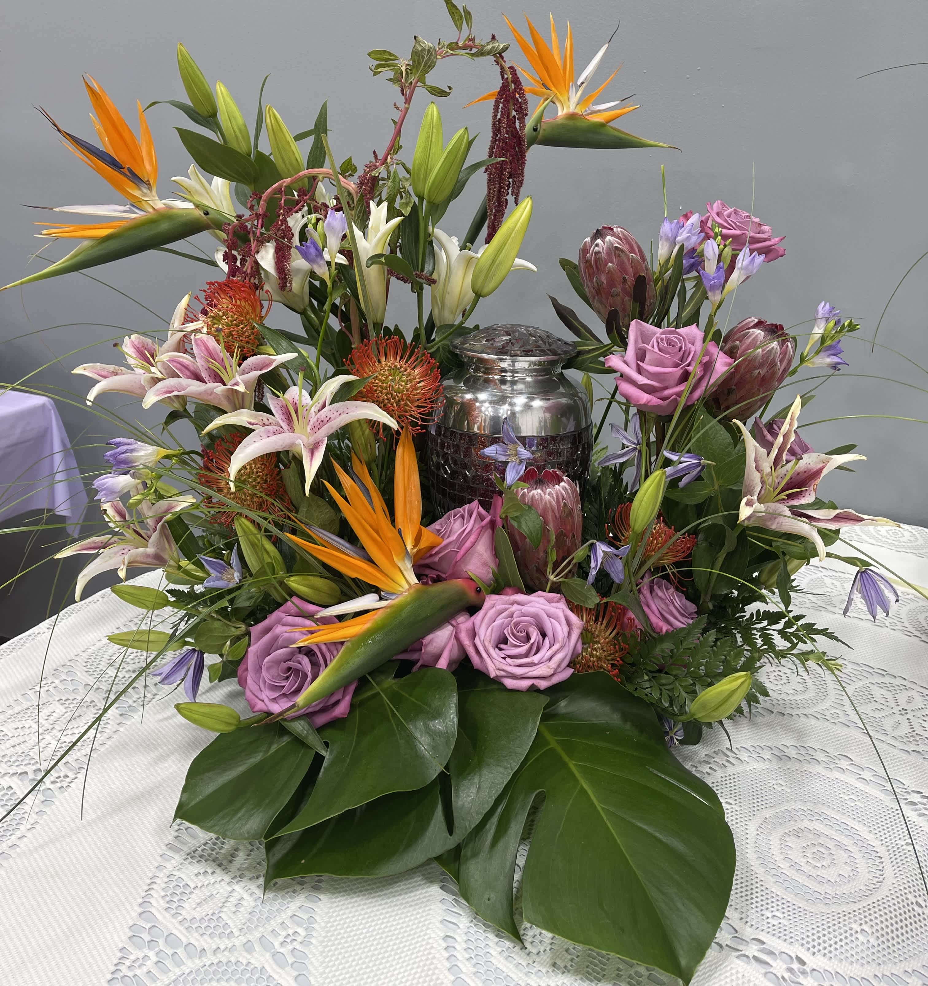 Tropical floral centerpiece with pink roses and lilies around a silver urn