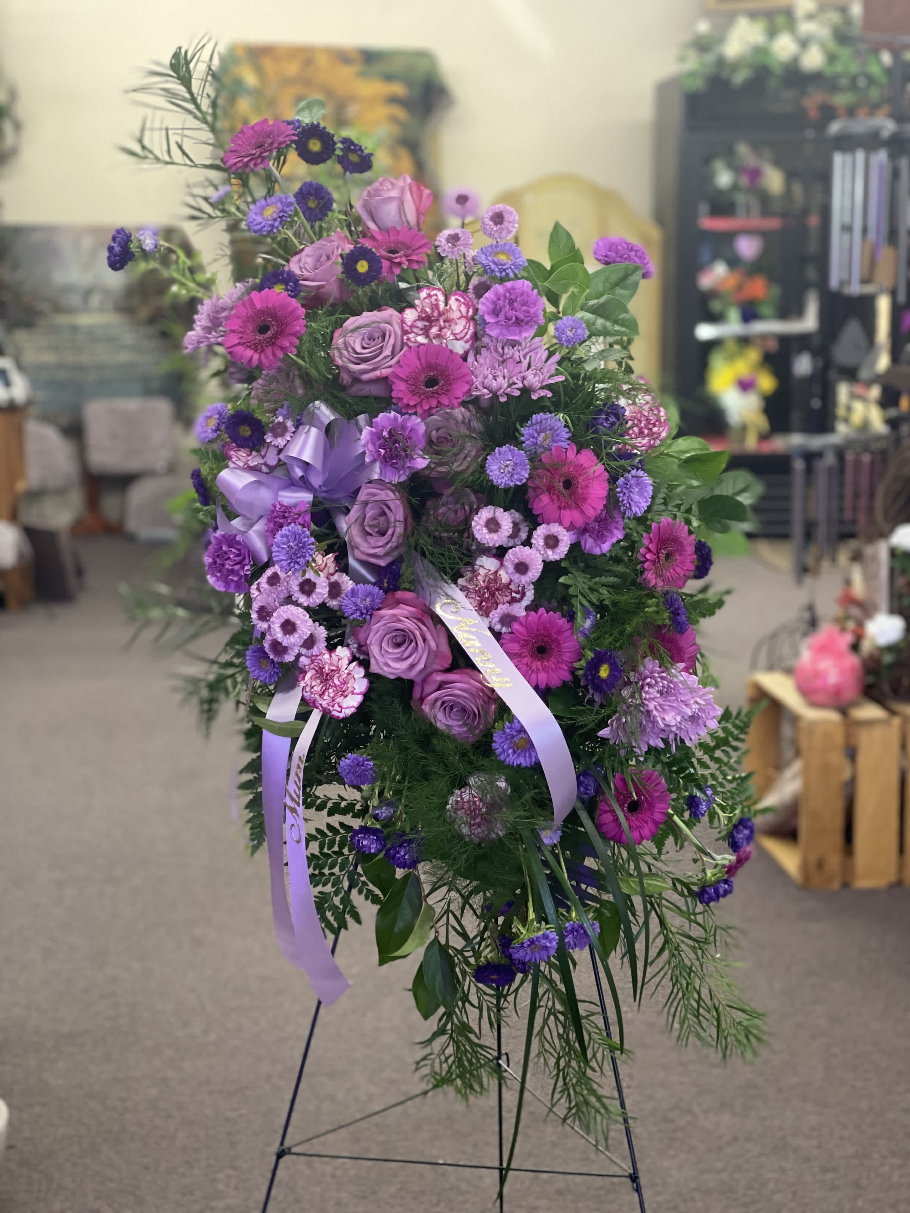 Standing spray of purple and pink flowers with lavender ribbons