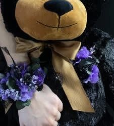 Black teddy bear with purple floral accents and a gold ribbon bow