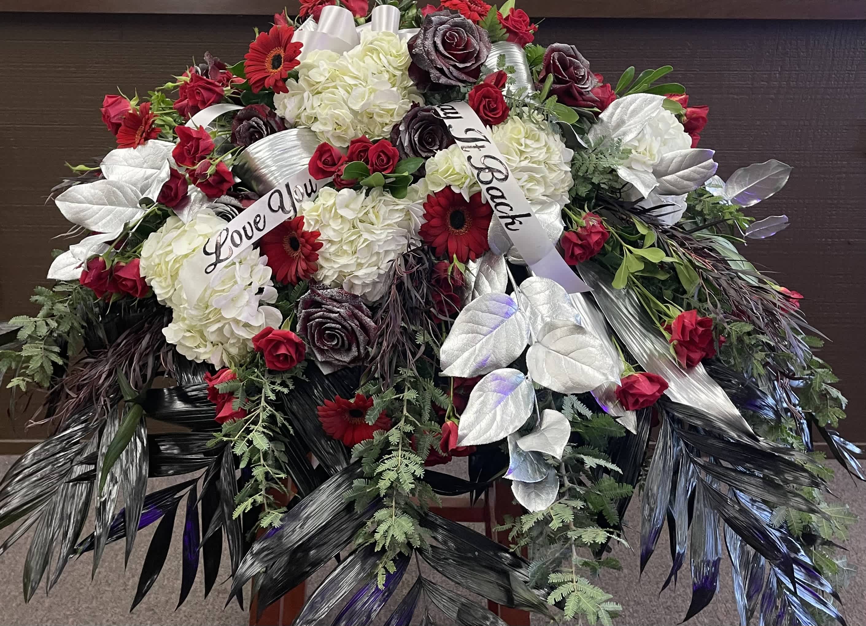Large floral spray with red roses, white hydrangeas, and silver leaves