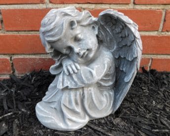 Small stone angel statue with folded wings resting its head on its arms