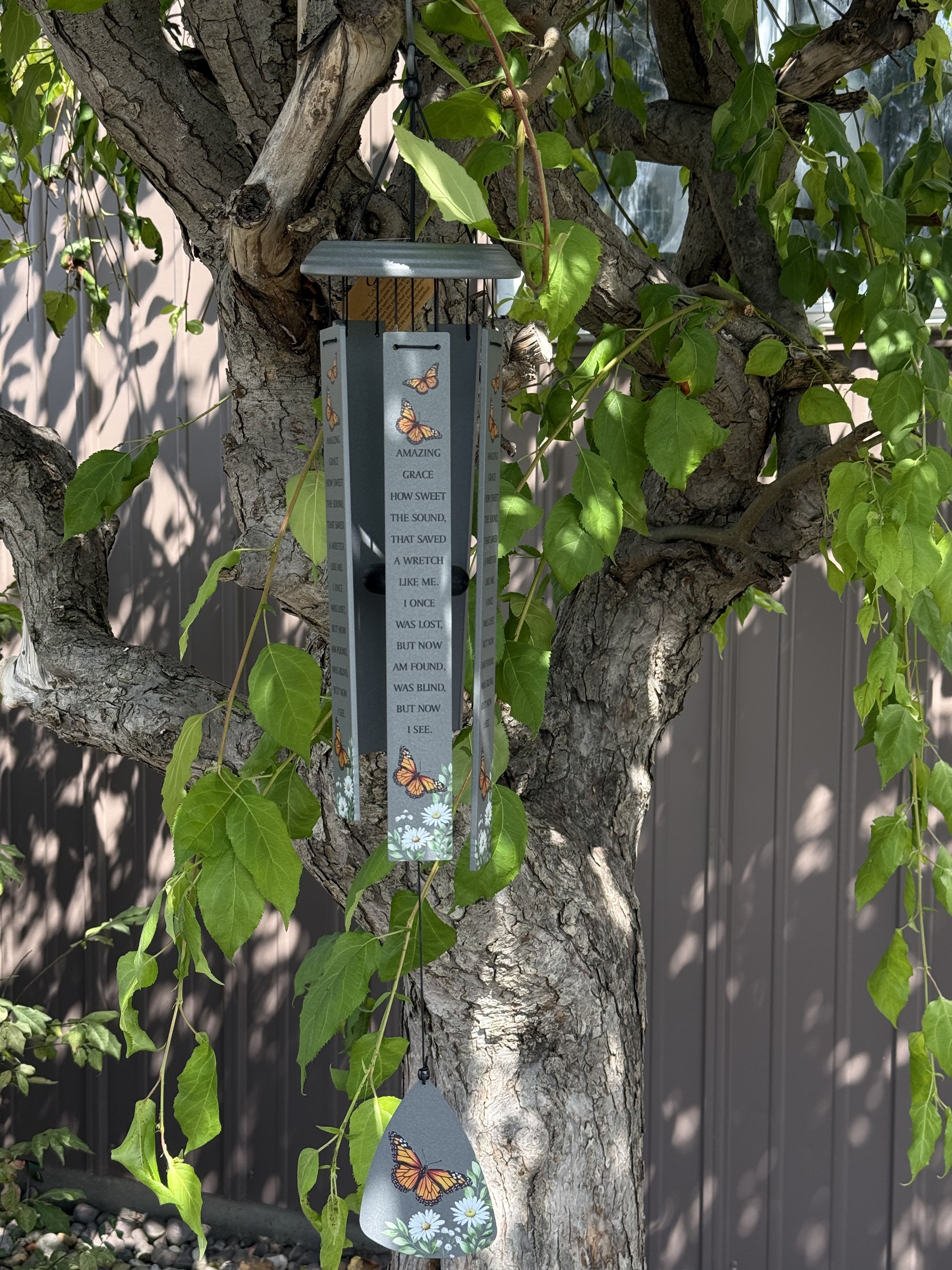 Butterfly-themed wind chime hanging from a tree branch