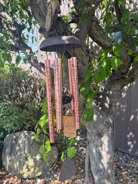 Copper wind chime hanging from a tree branch