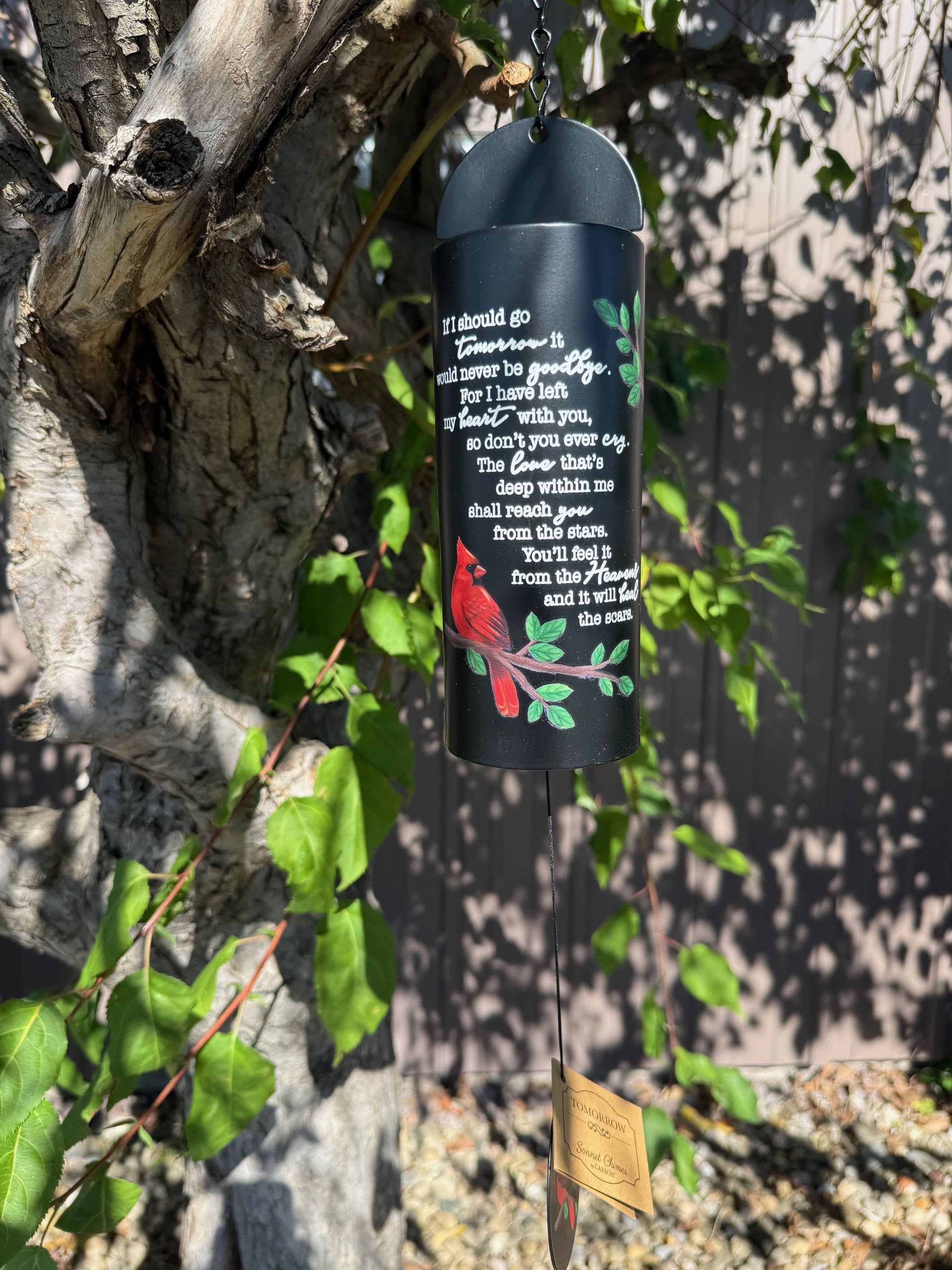 Black memorial wind chime hanging from a tree with a red cardinal design