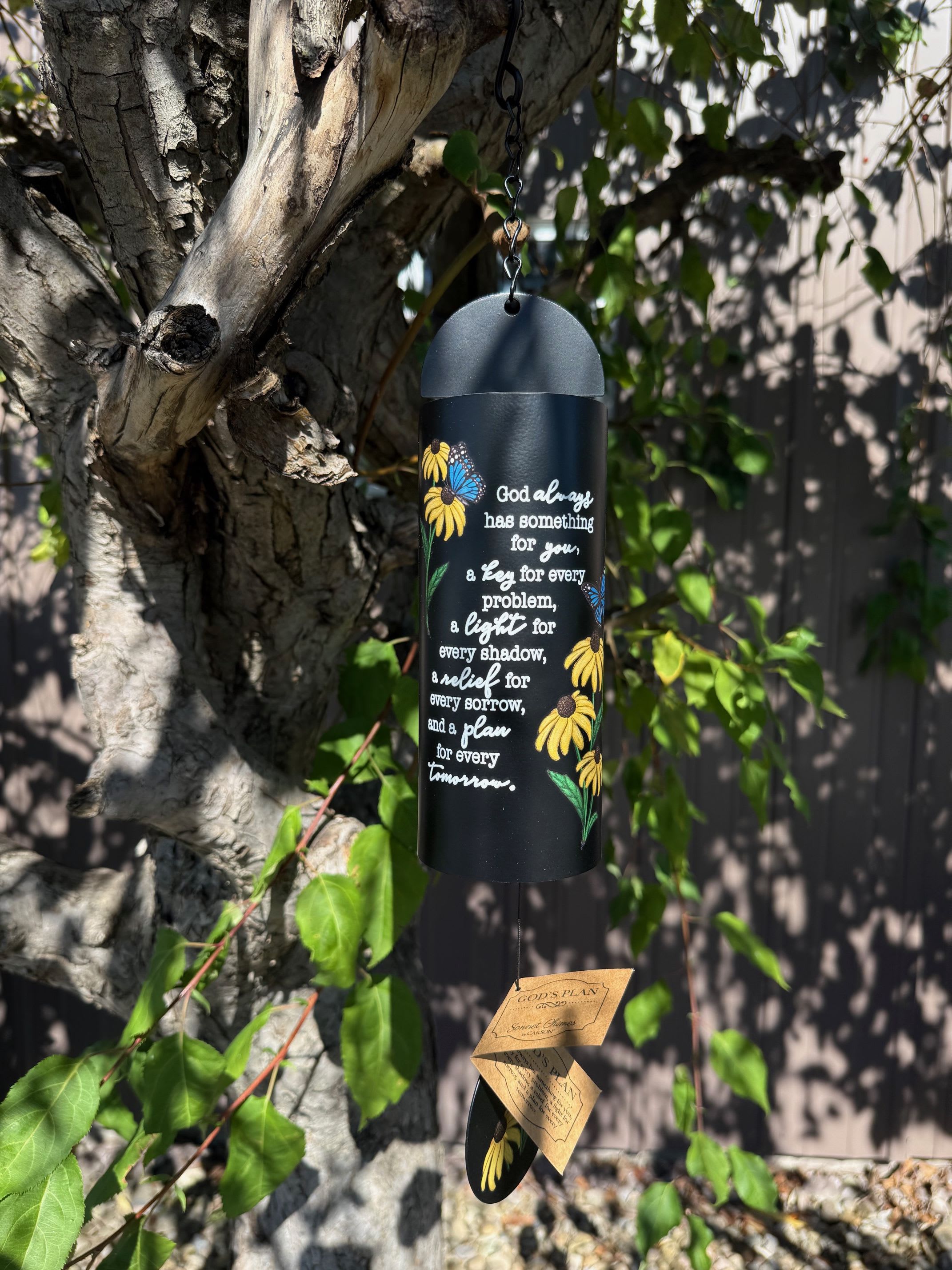 Black hanging wind chime with yellow flowers and white text
