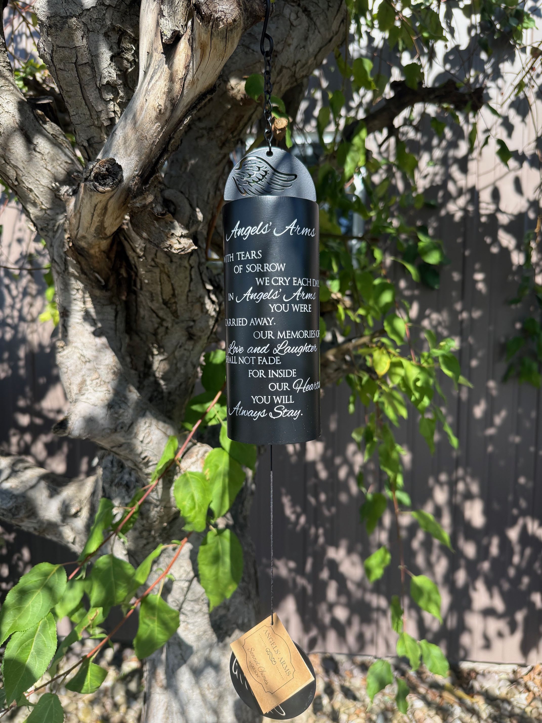 Black memorial wind chime hanging from a tree branch