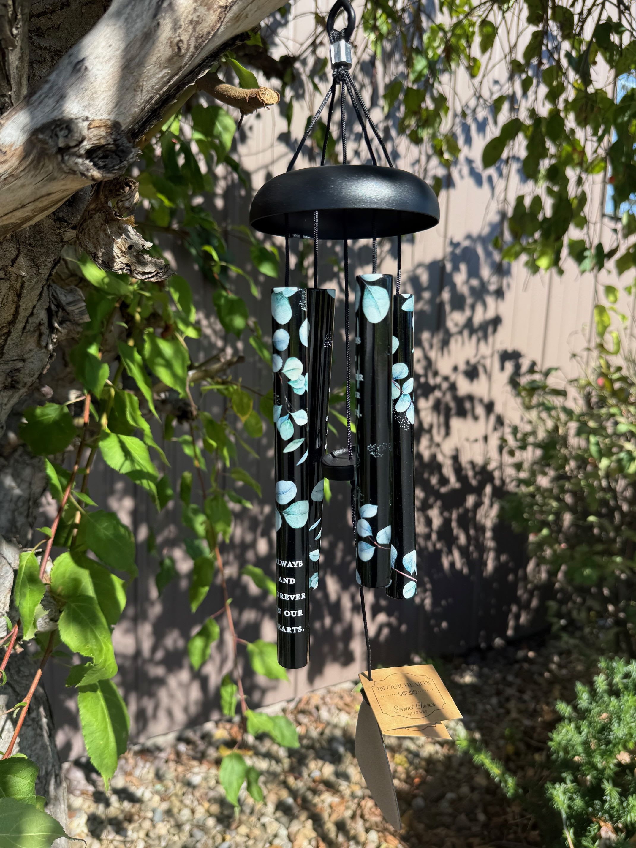 Black memorial wind chime hanging outdoors with blue leaf accents