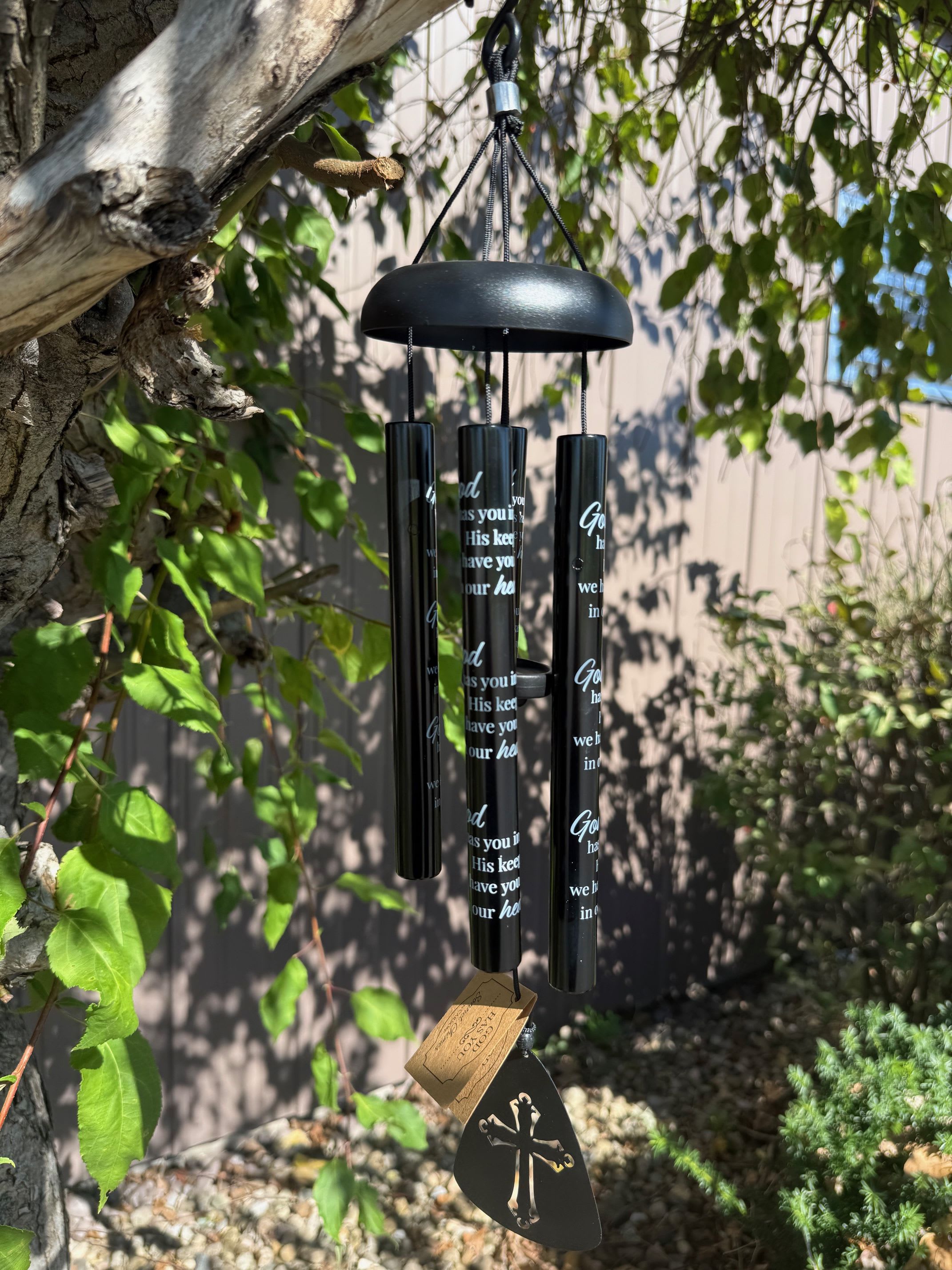 Black memorial wind chime hanging outdoors from a tree