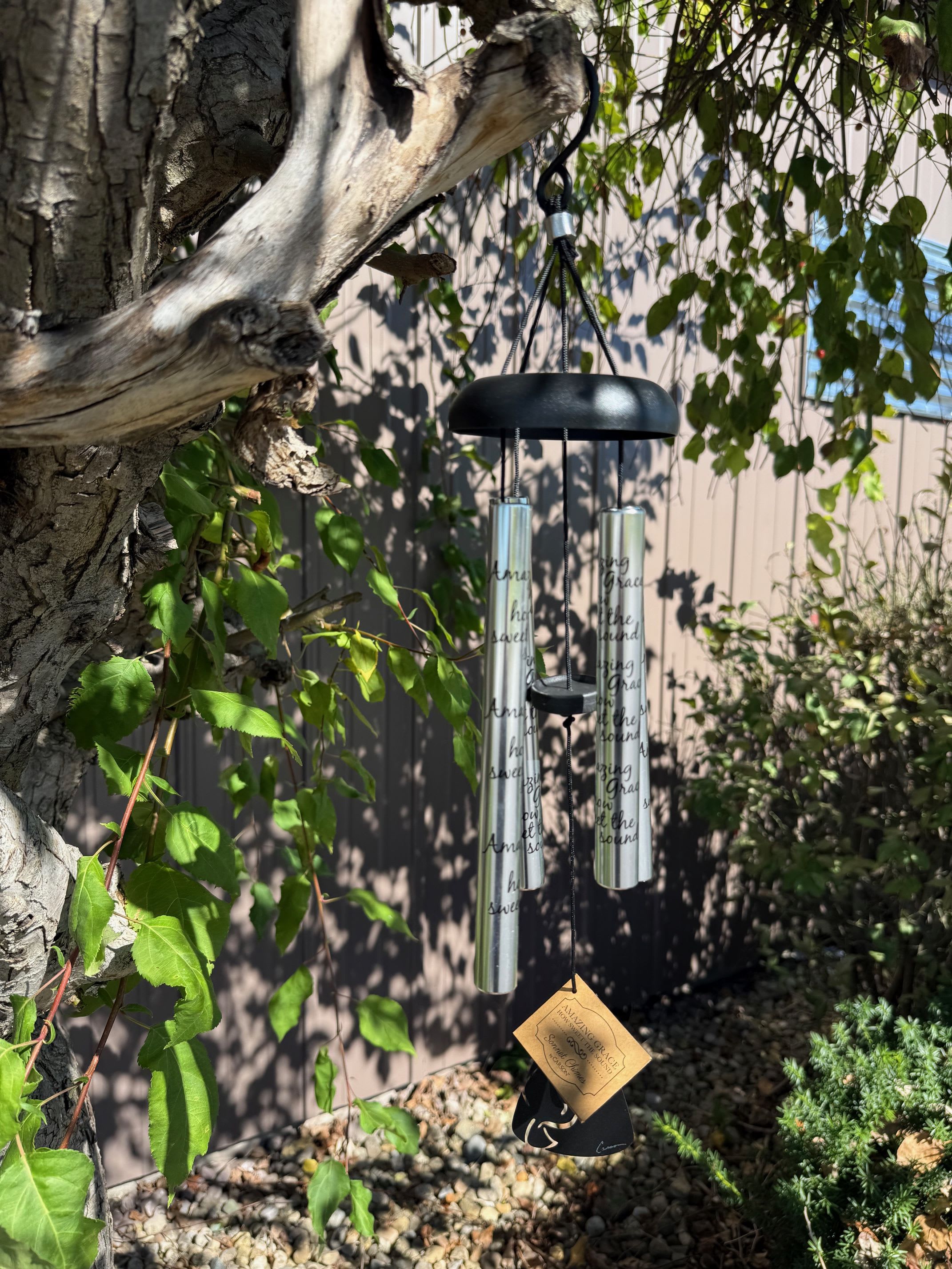 Hanging silver wind chime on a tree branch outdoors