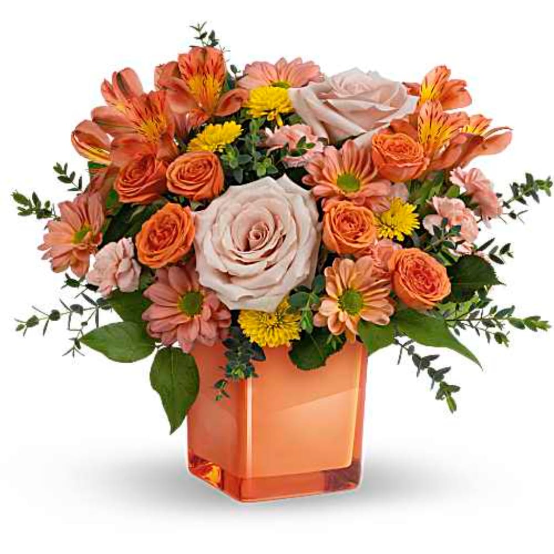Orange and blush mixed bouquet in a square glass vase