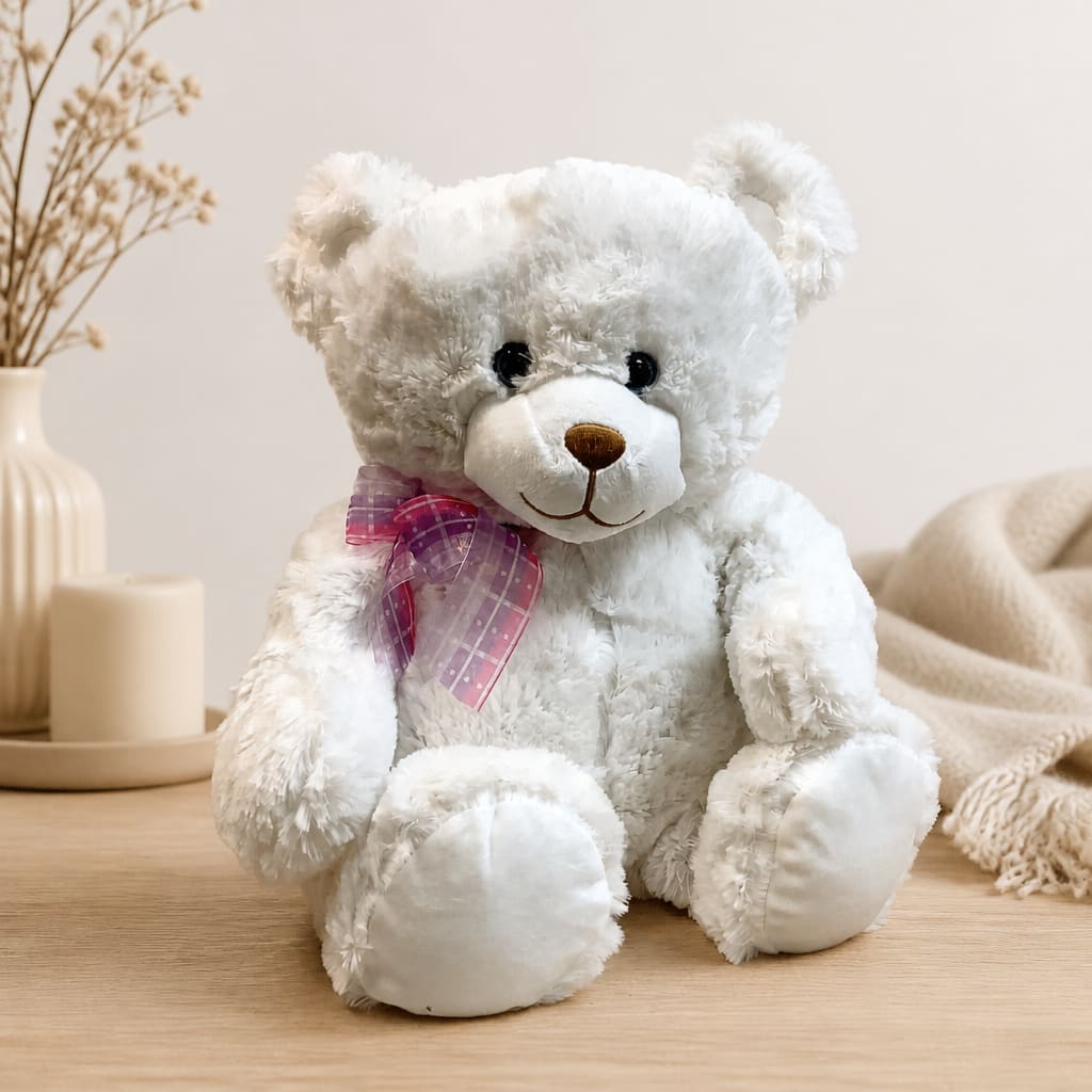 White teddy bear with a pink ribbon sitting on a table