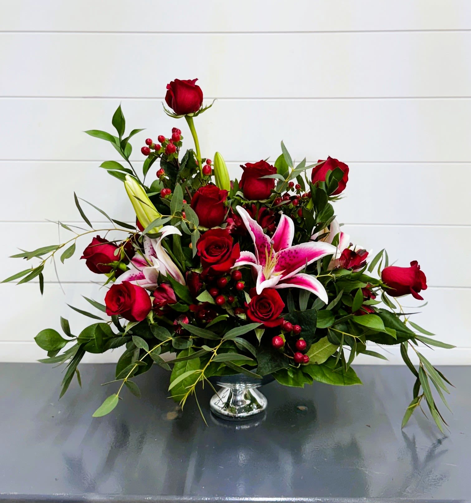 Red roses and pink lilies arranged in a silver vase