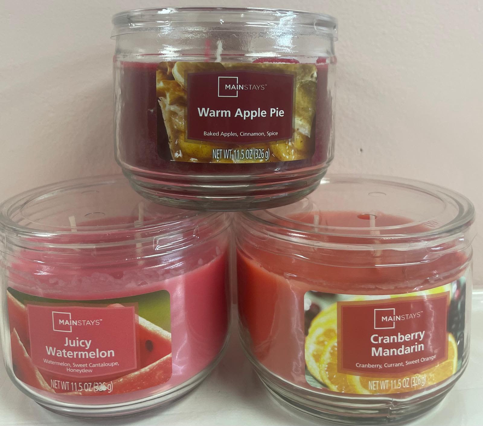 Set of three scented glass jar candles stacked in a small pyramid on a light background.