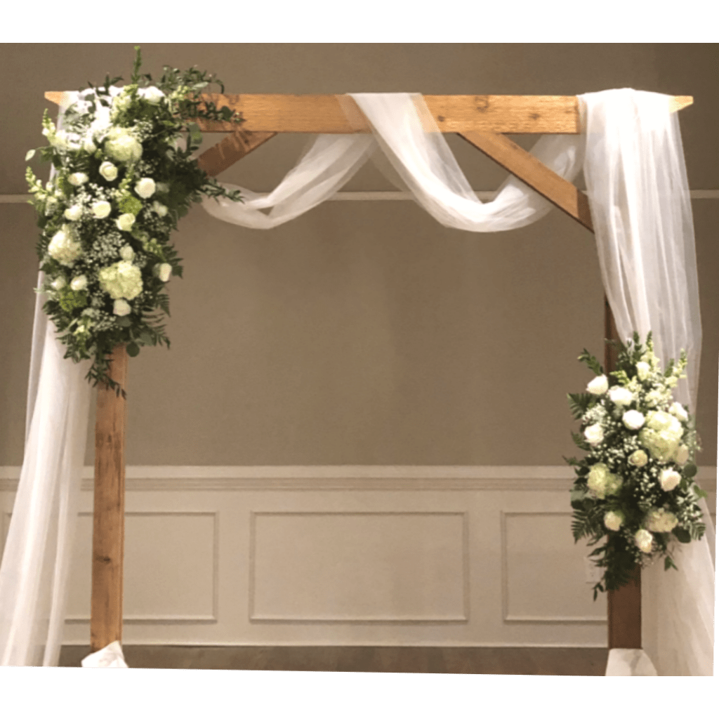 White floral arrangements on a wooden wedding arch with sheer draping
