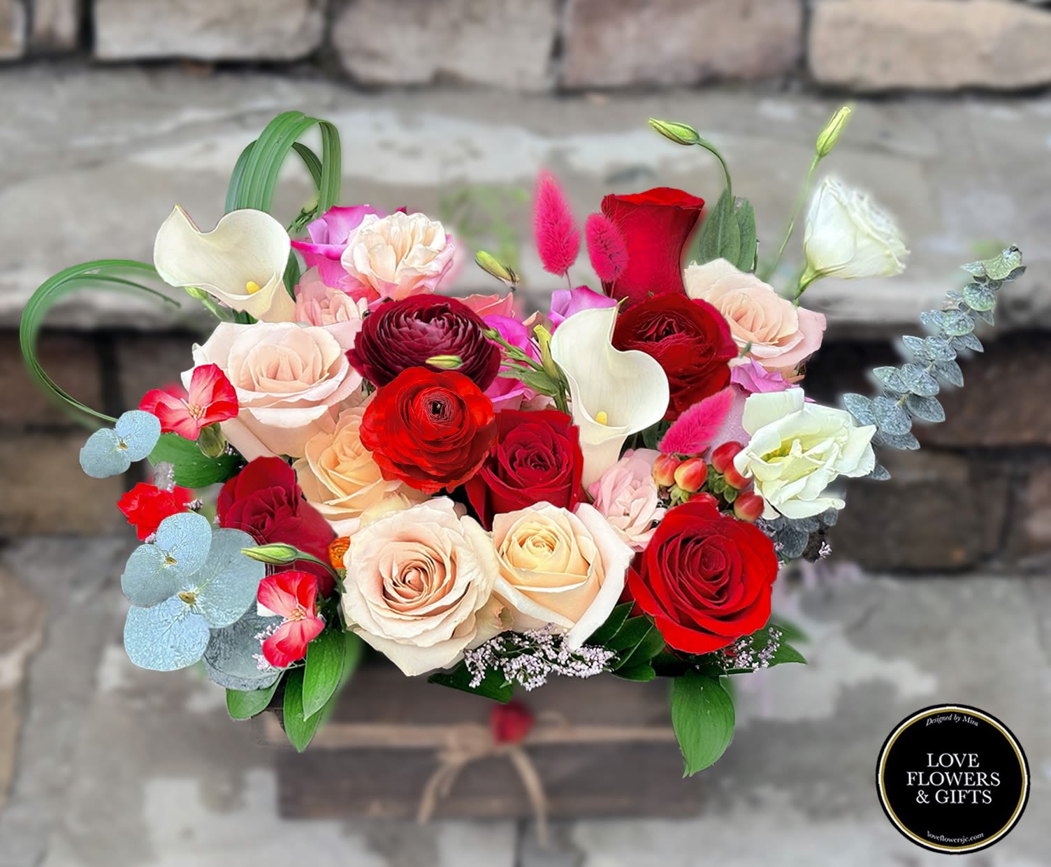 Rectangular wooden box filled with red and blush roses, white calla lilies, and mixed accent blooms