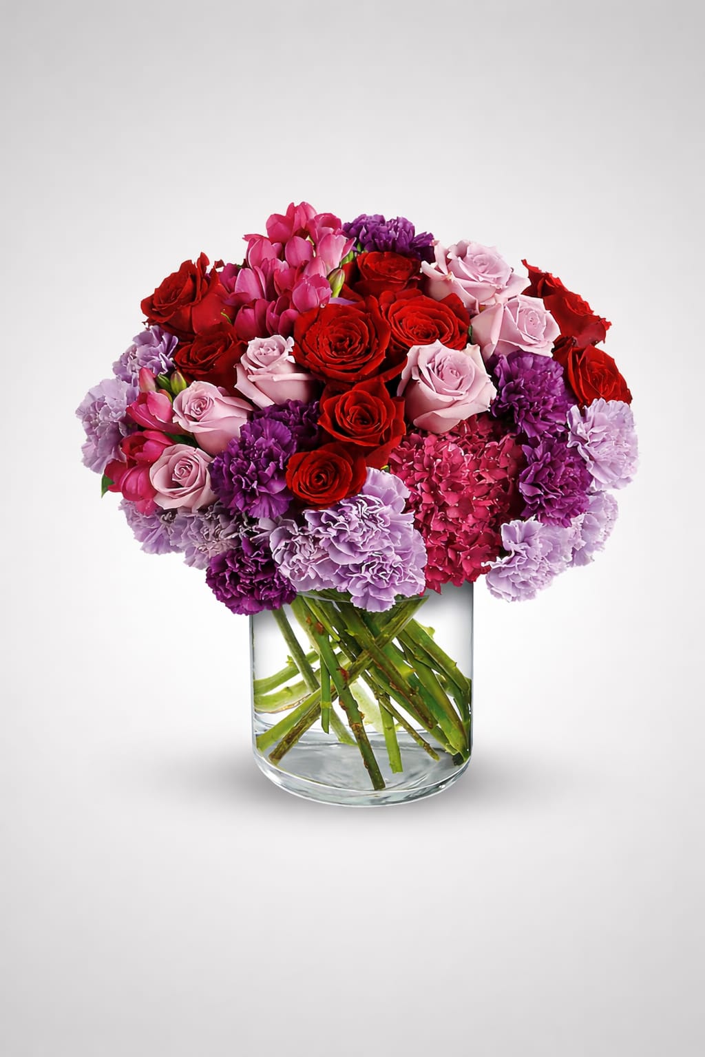 Bouquet of red and pink roses with purple carnations in a glass vase