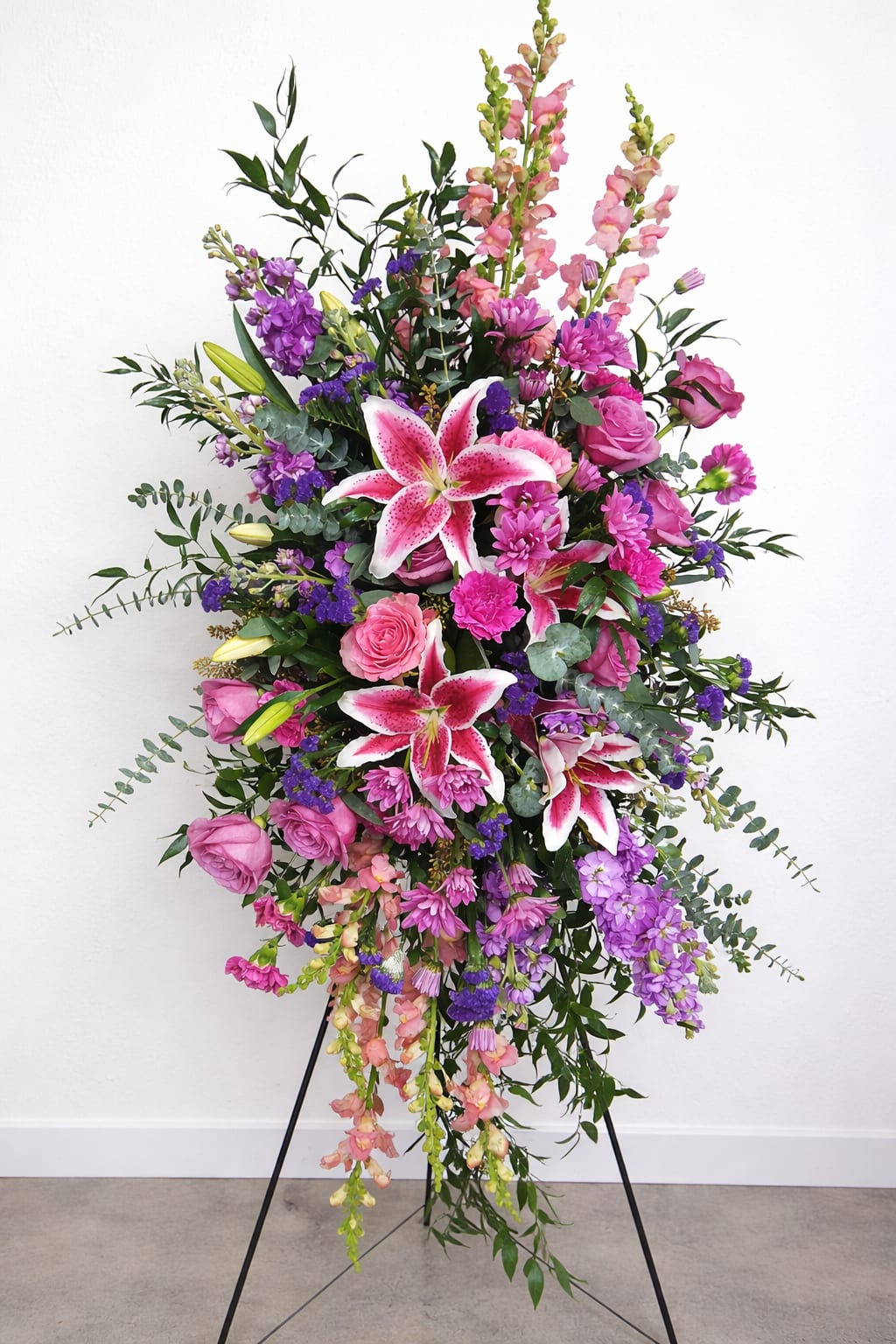 Tall standing floral spray with pink lilies and roses in pink and purple tones