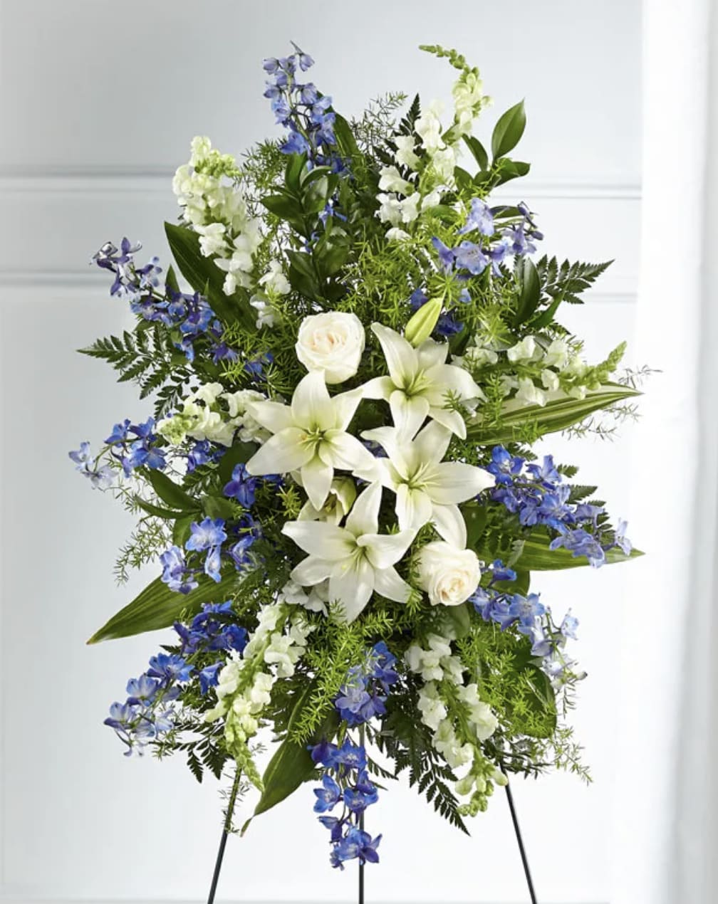 Tall standing floral spray with white lilies and blue flowers