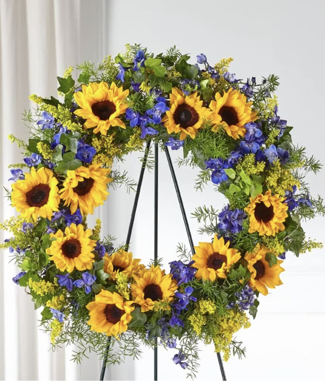 Sunflower wreath with blue and yellow flowers on a stand