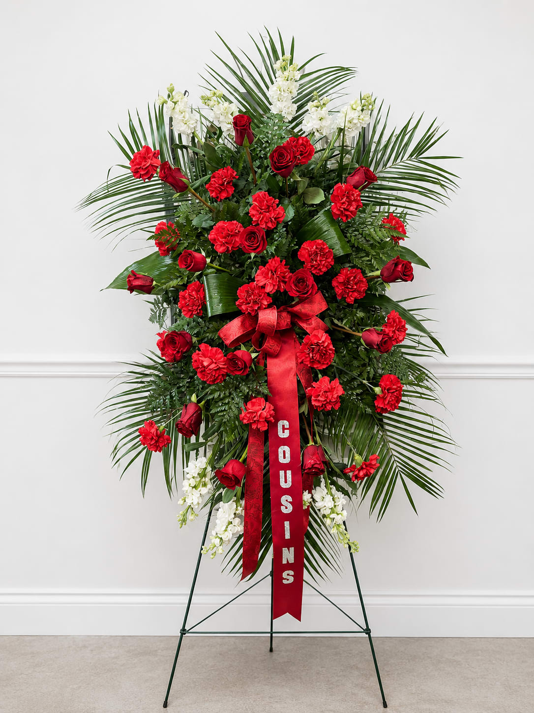 Standing red and white floral spray on an easel with a ribbon