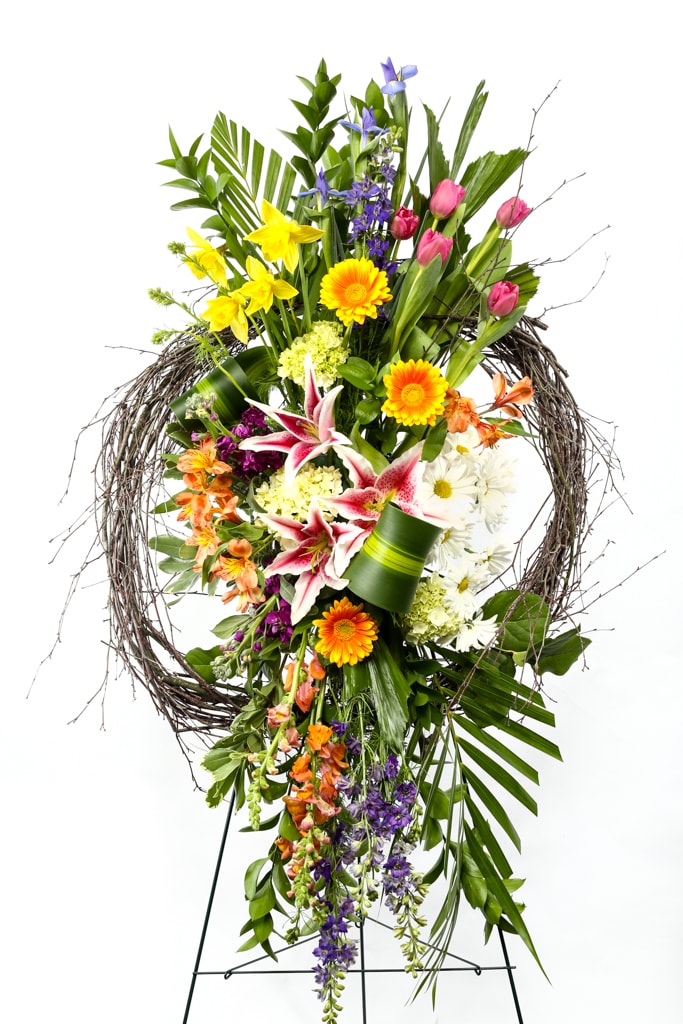 Tall floral standing spray with mixed blooms in a twig wreath frame