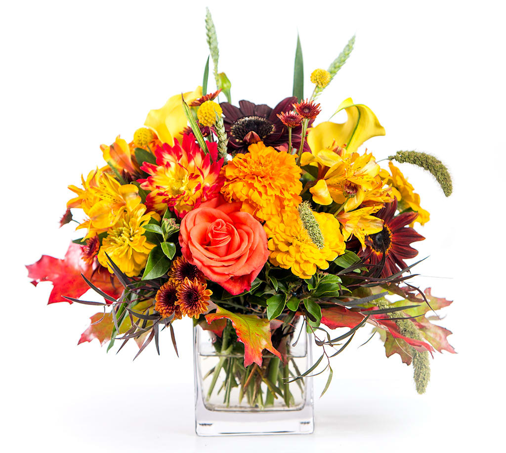 Autumn bouquet of orange and yellow flowers in a clear glass vase