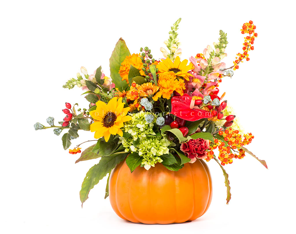 Fall bouquet in a pumpkin container with sunflowers and orange blooms