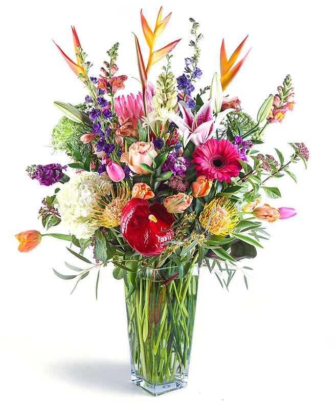 Mixed bouquet in a clear glass vase with pink, orange, purple, and white blooms