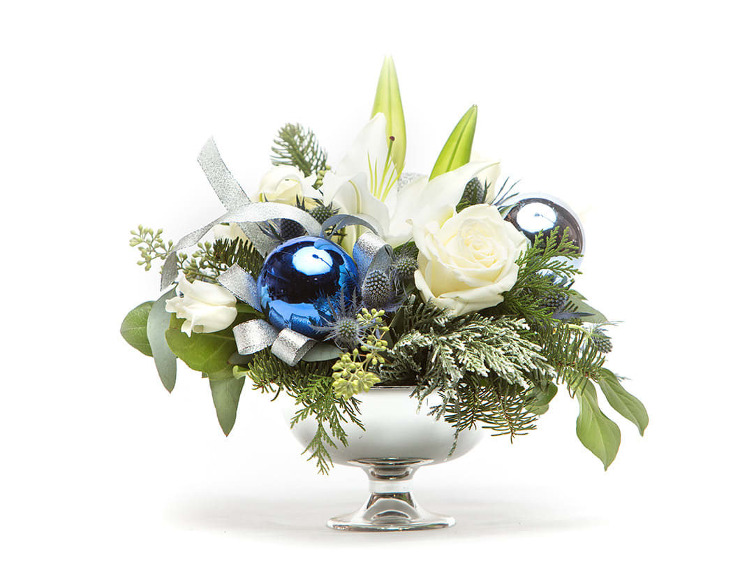White roses and lilies in a silver compote with blue ornaments